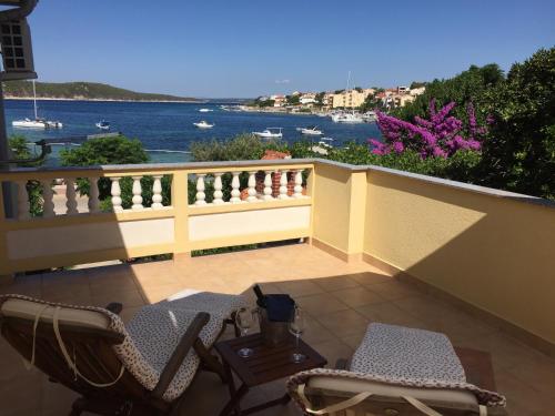 einen Balkon mit Stühlen und Blick auf das Wasser in der Unterkunft Apartments and Rooms Villa Luci in Barbat na Rabu