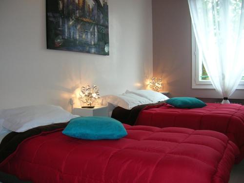 ルーアンにあるGite Seineの赤いカバー付きのベッド2台が備わる客室です。