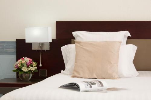 a book laying on top of a bed with a pillow at Alliance Lille - Couvent Des Minimes in Lille