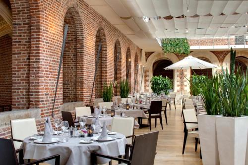a restaurant with white tables and chairs and brick walls at Alliance Lille - Couvent Des Minimes in Lille