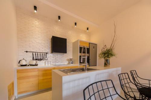 a kitchen with a sink and a counter with chairs at Villa Myrto in Líndos