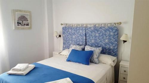 1 cama azul y blanca con cabecero azul y almohadas en Apart. Céntrico San Miguel en Córdoba