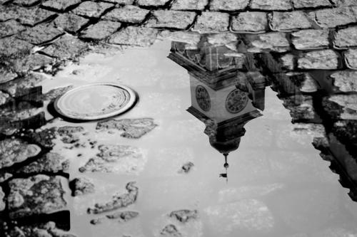 a reflection of a clock in a puddle of water at Penzion a wellness U Třeboňské madony in Třeboň