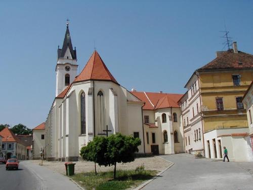 a church with a steeple and a person walking in front of it at Penzion a wellness U Třeboňské madony in Třeboň