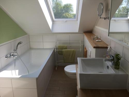 Un baño con lavabo, inodoro y ventana. en SEASIDE APARTMENTS - MOSSY GREEN, en Eckernförde