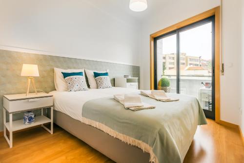 a bedroom with a large bed with a large window at Camões Executive Flat in Porto