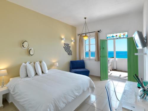 1 dormitorio con 1 cama blanca y 1 silla azul en Alikaki Kimolos, en Kimolos