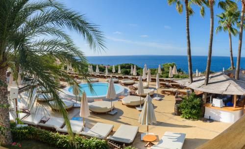 ośrodek z basenem, krzesłami i palmami w obiekcie Destino Pacha Ibiza w Talamance