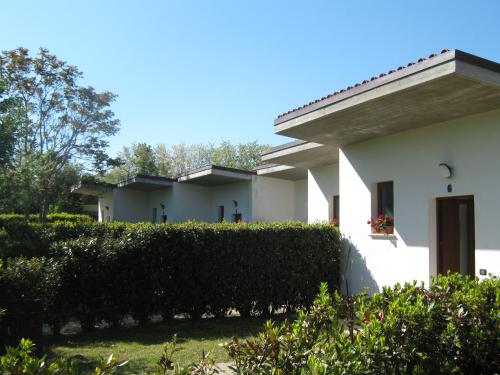 a white house with a hedge in front of it at B & B OASI in Rosciano