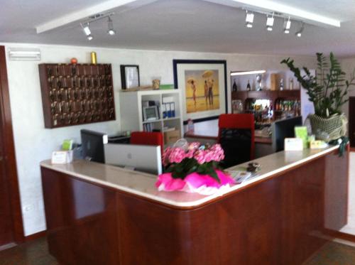 a lobby with a reception counter with pink flowers at Hotel Viking in Rimini