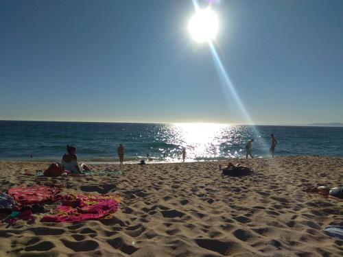 a group of people on a beach with the sun at Quarto privado Alentejo Litoral in Grândola