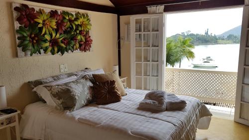 a bedroom with a large bed with a large window at Pousada Costa do Sapê in Angra dos Reis