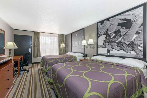 a hotel room with two beds and a desk at Super 8 by Wyndham Longview/North in Longview