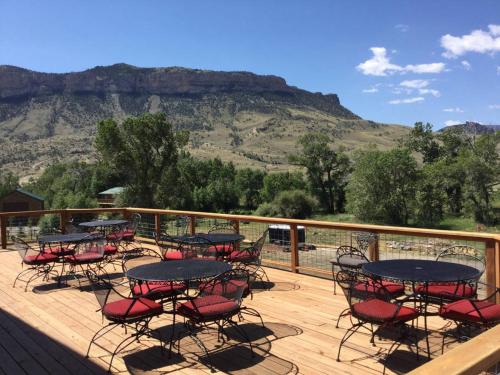 a deck with tables and chairs with mountains in the background at Eycat Lodging Company in Wapiti