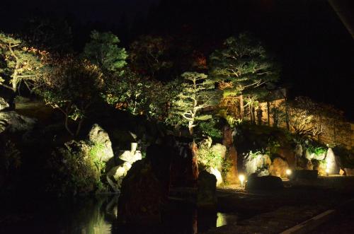 a garden at night with trees and lights at 高野山 宿坊 不動院 -Koyasan Shukubo Fudoin- in Koyasan