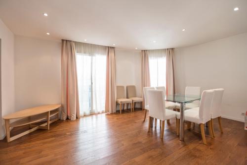 une salle à manger avec une table en verre et des chaises blanches dans l'établissement Imperial Apartment by Connexion, à Cannes