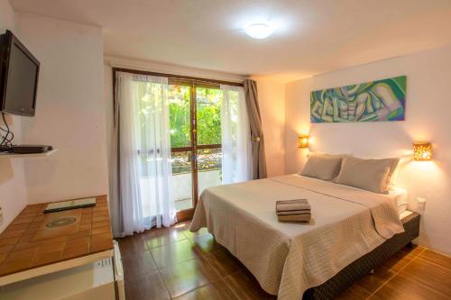 a bedroom with a bed and a large window at Pousada Borboleta in Morro de São Paulo