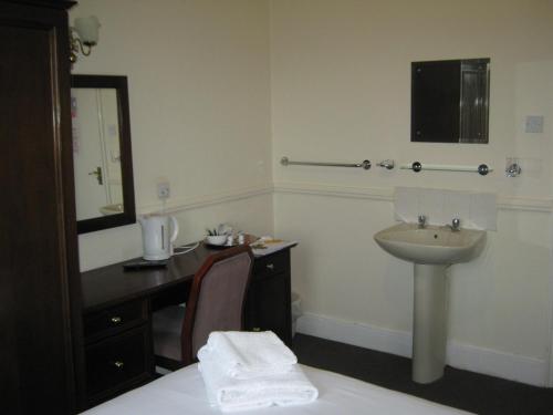 een badkamer met een wastafel en een bureau met een spiegel bij Rose and Crown Hotel in Haverhill