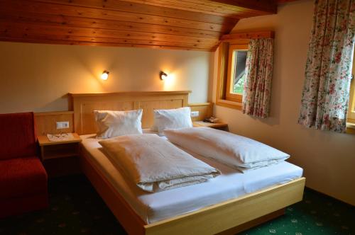 a bedroom with a bed with white sheets and a window at Pension Trillerhof in Ramsau am Dachstein