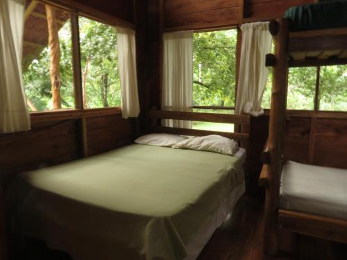 a bedroom with two bunk beds and two windows at Vocaré Finca Agroecológica in Upala
