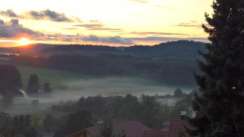 a misty sunrise with the sun rising over a city at Familienzimmer Bastian in Haibach