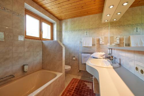 y baño con bañera, lavamanos y bañera. en Pension Bergland, en Lech am Arlberg