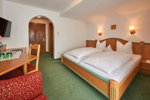 a bedroom with a bed and a desk and a chair at Pension Bergland in Lech am Arlberg