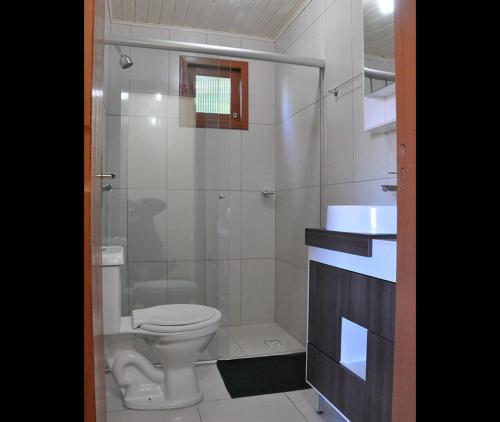 a bathroom with a toilet and a glass shower at Hospedagem Encanto da Serra Rural in Cambara do Sul