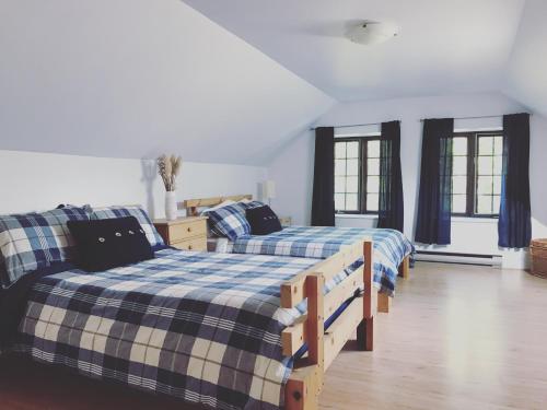 two beds in a room with two windows at Chalet Rustique CRDS Tremblant in Lac-Superieur