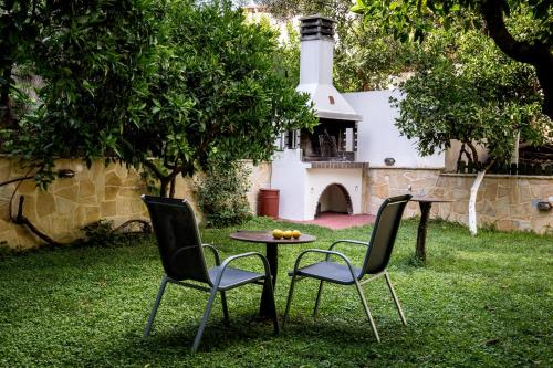 2 Stühle und ein Tisch in einem Hof mit einem Leuchtturm in der Unterkunft Oasis Apartments in Tolo