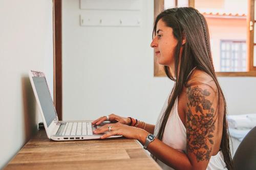 a woman sitting at a table using a laptop computer at CLH Suites Ilha Grande in Abraão