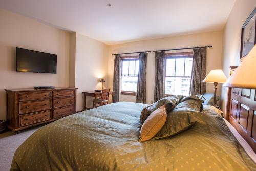 a bedroom with a bed with a television and windows at The Lodge at Mountaineer Square in Mount Crested Butte