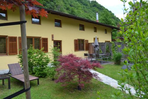 a yellow house with a bench in the yard at Počitniška hiša Lazar in Kobarid
