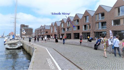a group of people walking on a sidewalk next to the water at Schnieke Hüsing in Wismar