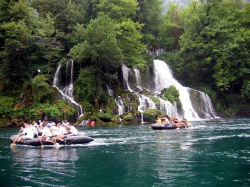 a group of people riding on tubes in the water near a waterfall at Viola i Detelina Apartments in Perućac