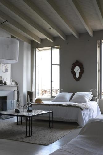 a white bedroom with a bed and a table at La maison sur la place in Penne-dʼAgenais