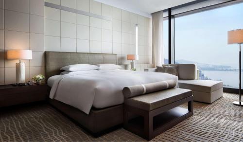 - une chambre avec un grand lit et une grande fenêtre dans l'établissement Grand Hyatt Dalian, à Dalian