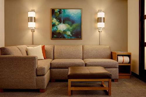 a living room with a couch and a painting at Hyatt Place Raleigh Durham Airport in Morrisville
