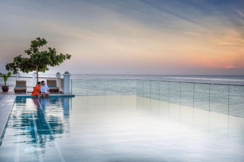a couple sitting on a bench next to the ocean at Park Hyatt Zanzibar in Zanzibar City