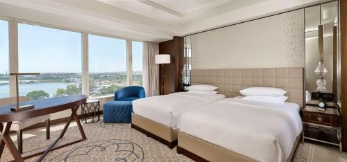 a hotel room with two beds and a desk and windows at Hyatt Regency Istanbul Atakoy in Istanbul