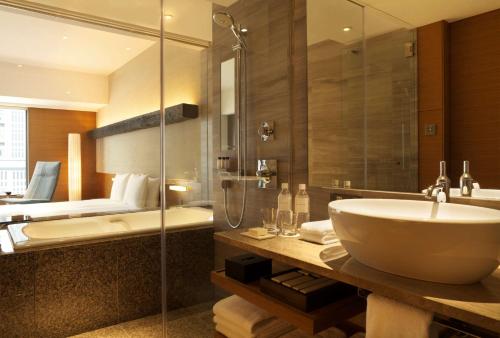 a bathroom with a tub, sink and mirror at Hyatt Regency Tokyo in Tokyo