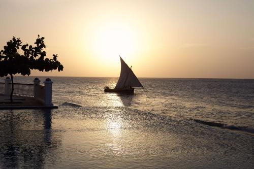 a sail boat in the ocean at sunset at Park Hyatt Zanzibar in Zanzibar City