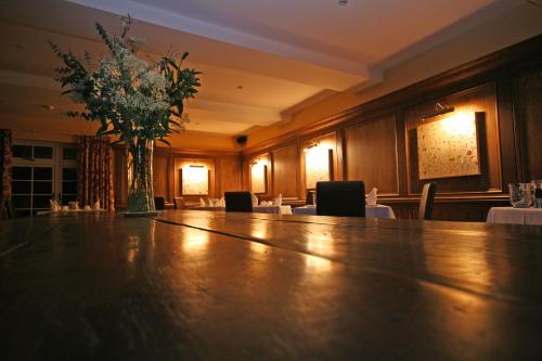 a large wooden table with a vase of flowers on it at Stocks Hotel in Sark
