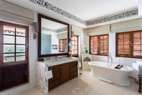 ein Badezimmer mit einer Badewanne, einem Waschbecken und einem Spiegel in der Unterkunft Park Hyatt Zanzibar in Zanzibar City