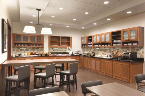 a large kitchen with wooden cabinets and tables and chairs at Hyatt Place Portland Airport/Cascade Station in Portland