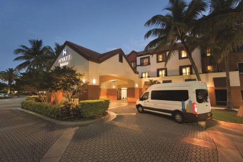 a white van parked in a parking lot in front of a building at Hyatt House Miami Airport in Miami