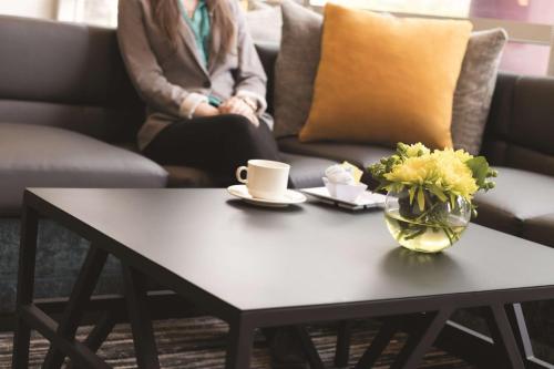 a woman sitting on a couch with a coffee table at Hyatt Place Chicago O'Hare Airport in Rosemont