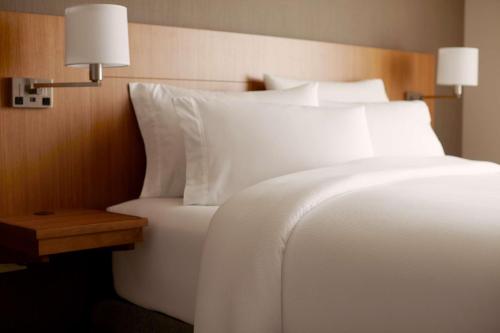 a bedroom with a bed with white sheets and a table at Hyatt Place Madison/Verona in Verona