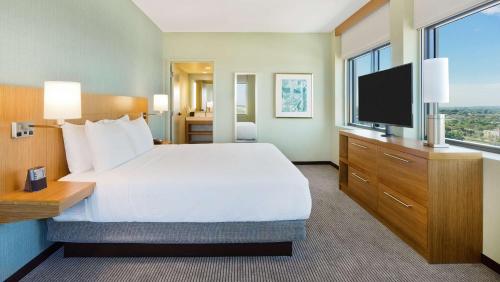 a hotel room with a bed and a flat screen tv at Hyatt Place Boca Raton in Boca Raton