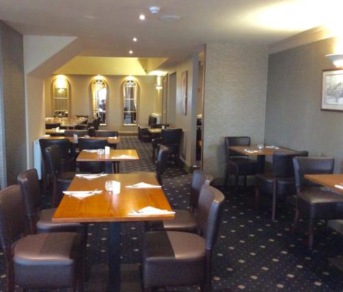 a dining room with wooden tables and chairs at King Alfred Hotel in Barrow in Furness